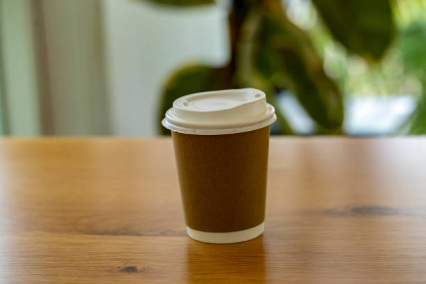 istock Plastic coffee cup with paper sleeves placed on a wooden table. Blurred background. 1746035634