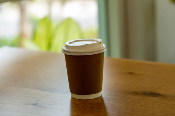 istock Plastic coffee cup with paper sleeves placed on a wooden table. Blurred background. 1746035635