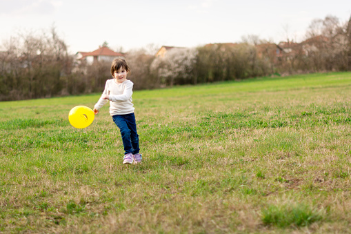 Full length of a child girl running whit yellow balloon outdoors