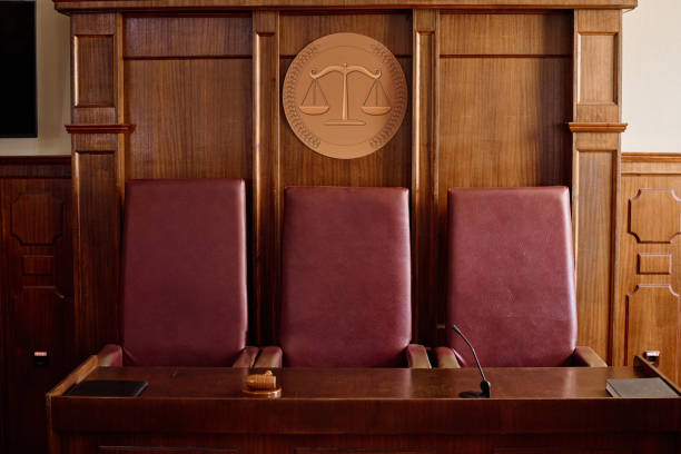 istock Wooden table with gavel, microphone and black leather folder with documents 1746051145