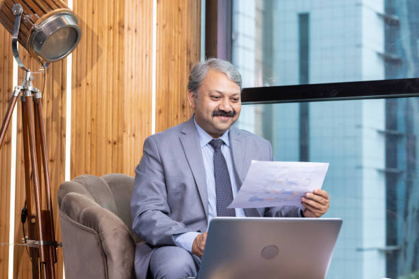 istock Indian businessman sitting on sofa and working on laptop at modern office 1746052259
