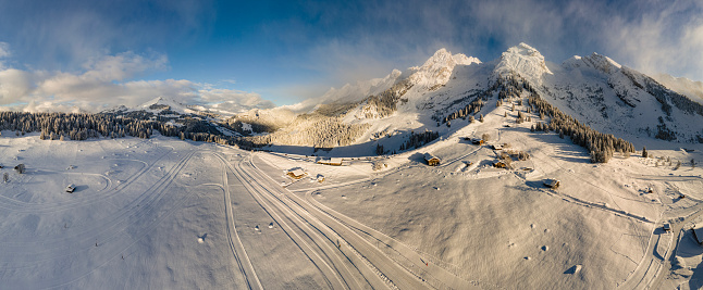 180° view from the assembly of 21 photographs taken with a drone.\nThe village of Confins is located at the bottom of the Clusaz valley, a ski resort of the same name, in the Aravis massif, in Haute-Savoie. In this part of the ski resort, Nordic skiing is practiced in winter, and golf in summer.