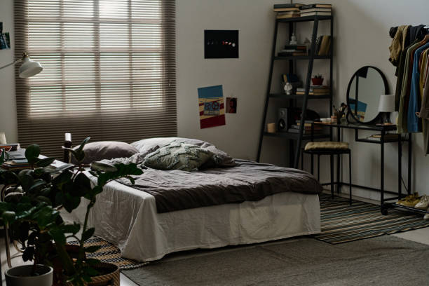 istock Comfortable double bed with grey blanket and cushions standing by window 1746068007