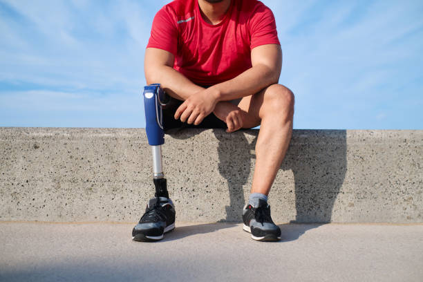 istock Young man with a prosthetic leg sitting on a retaining wall in the beach 1746069170
