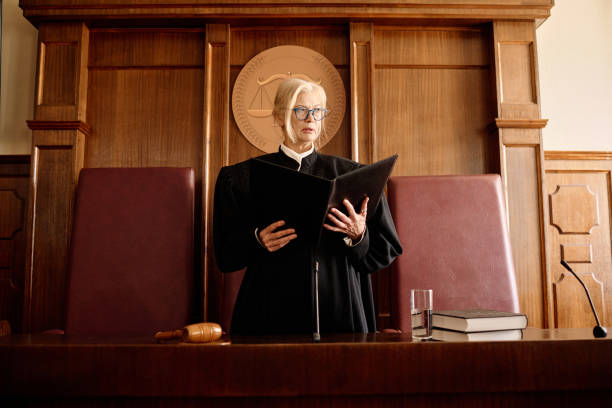 istock Confident mature blond female judge with open folder standing by desk 1746069180
