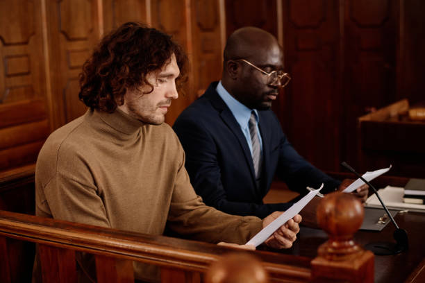 istock Young male suspect and his attorney looking through juridical documents 1746070943