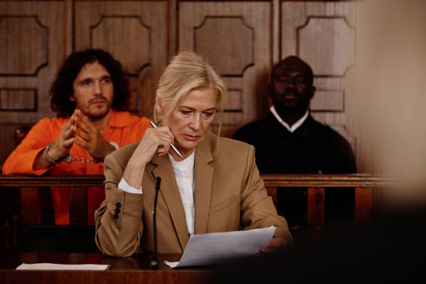istock Serious mature female lawyer looking through juridical document during trial 1746072702