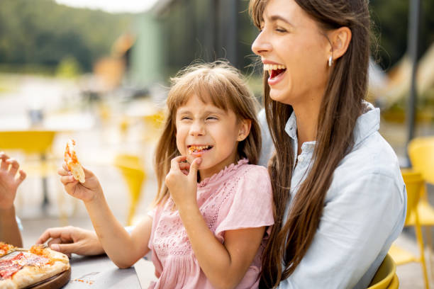 istock Cheerful mom with her little daughter eating pizza 1746079375
