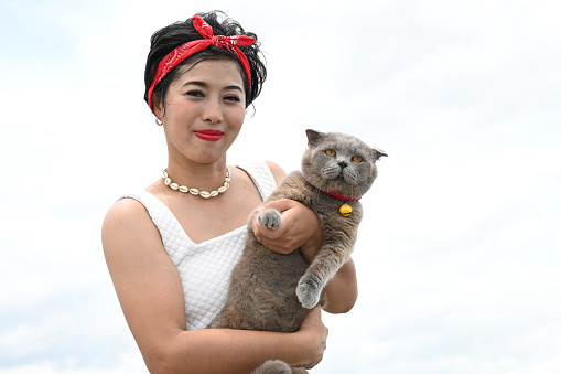 Pretty Asian female hold her the orange eyes of a Scottish Fold cat on white background.