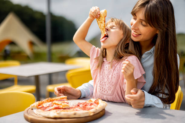 istock Cheerful mom with her little daughter eating pizza 1746101159
