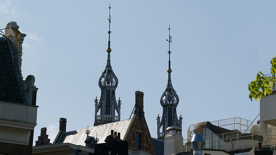 A weathervane on a slate roof against a blue sky with clouds. Room has been left for copy space.