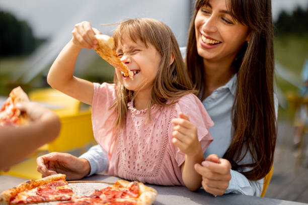 istock Cheerful mom with her little daughter eating pizza 1746102796