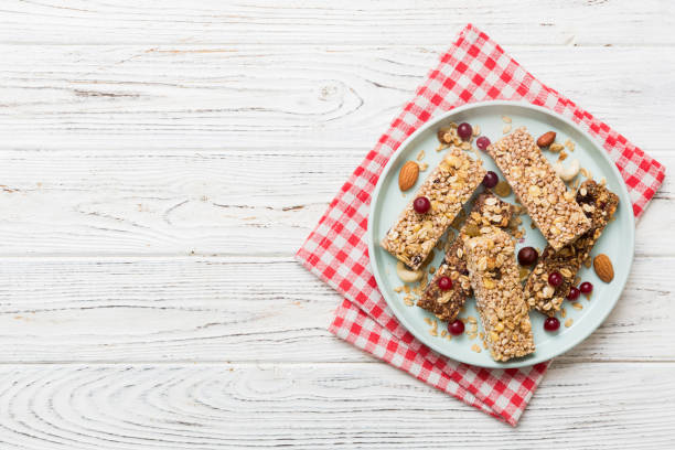 varias barras de granola sobre el fondo de la mesa. barras de granola de cereales. barritas de desayuno de superalimentos con avena, nueces y bayas, de cerca. concepto de superalimento - protein bar cereal oat cranberry fotografías e imágenes de stock