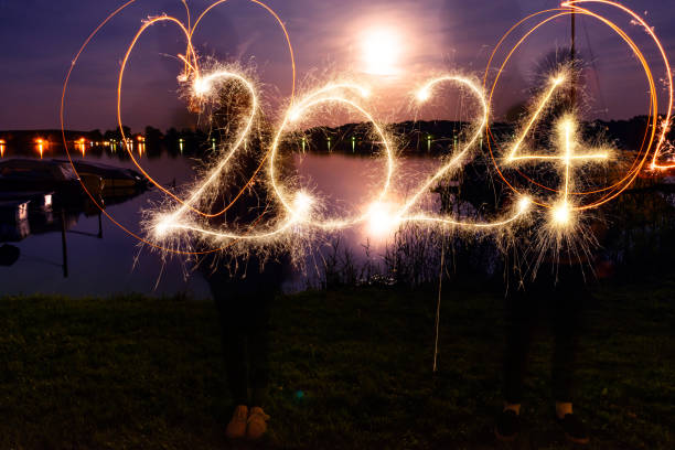 hände schreiben mit wunderkerze 2024 - frohes neues jahr - sparkler sparks new years eve human hand stock-fotos und bilder