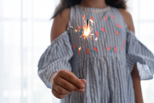 Little girl out of focus background with sparkler in hand in foreground