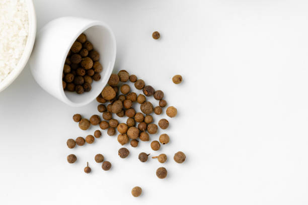 Allspice in a wooden spatula on a white background