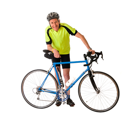 Full length shot of a mature male cyclist standing at his bike looking at the camera with a smile.  Isolated on white.