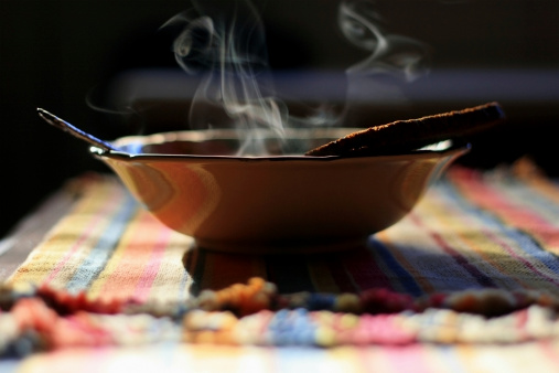 A bowl of fresh, hot and steaming soup -- slide bread on the side of the bowl.