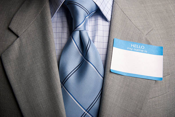 Confident young man in a white shirt and patterned tie, presenting a business card. His professional appearance suggests he is ready for networking and business engagements