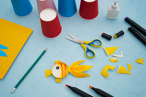 6 - Step by step diy process. Kids craft multicoloured fish from a paper coffee cup, zero waste concept.