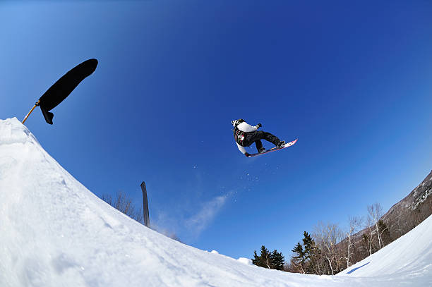 istock Snowboarder  performs freestyle stunt in terrain park against blue sky 174616324