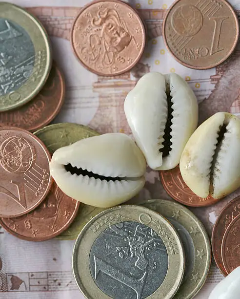 Coins,paper money and shells. Focus on coins and cowrishells.