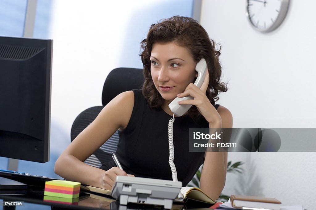 Secretary A young woman looks at the monitor and speaks by phone. Adult Stock Photo