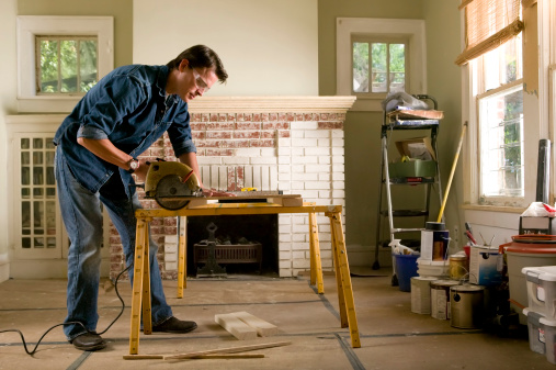 Single man measuring and cutting lumber while renovating his his home interior.