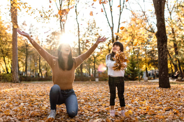 istock Mother and daughter having fun playing with autumn leaves 1746184872
