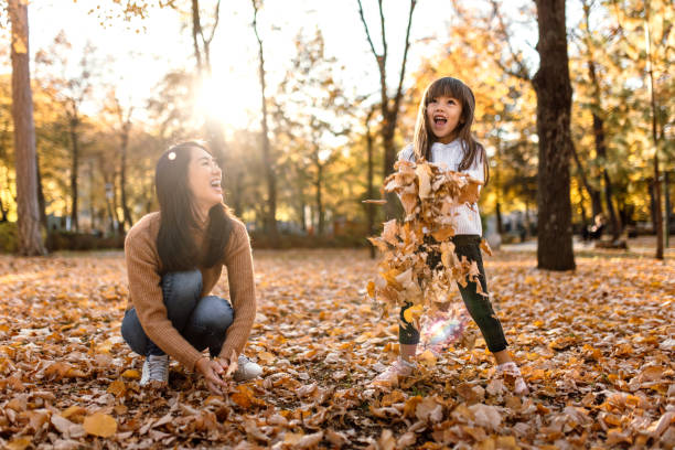 istock Mother and daughter having fun playing with autumn leaves 1746184886