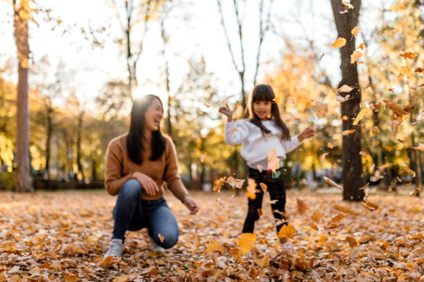 istock Mother and daughter having fun playing with autumn leaves 1746184902