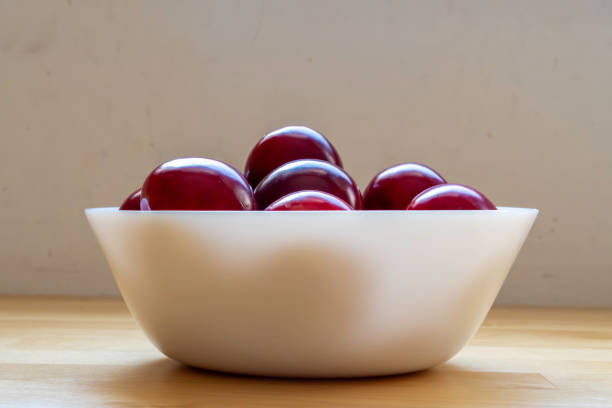 istock Red sour plums in a white ceramic bowl. Side view. 1746187222
