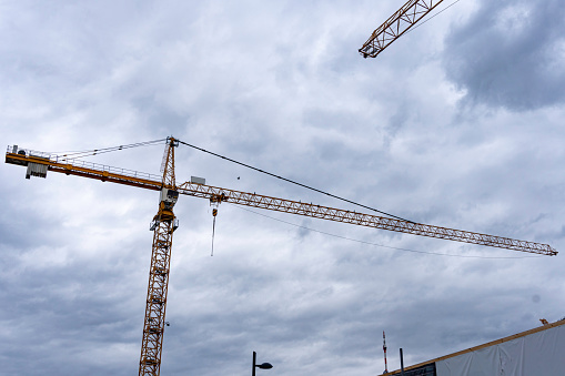 Tower crane on a construction site against cloudy sky.