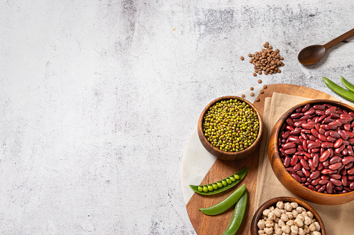 Top view of an assortment of legume family rich on vegan protein such as kidney beans, chickpeas, pea pods, lentils and green soy beans with copy space on the counter top
