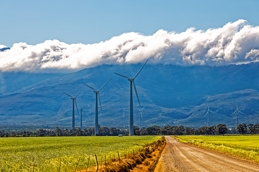 Large wind turbines in the Gouda wind farm with cloud covered Obiekwaberge mountains in the background near Gouda, Western Cape, South Africa