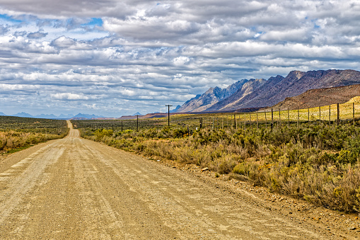 Long dusty gravel road running next to Langeberg Mountains  towards Van Wyksdorp in the Little Karoo in the Western Cape, South Africa