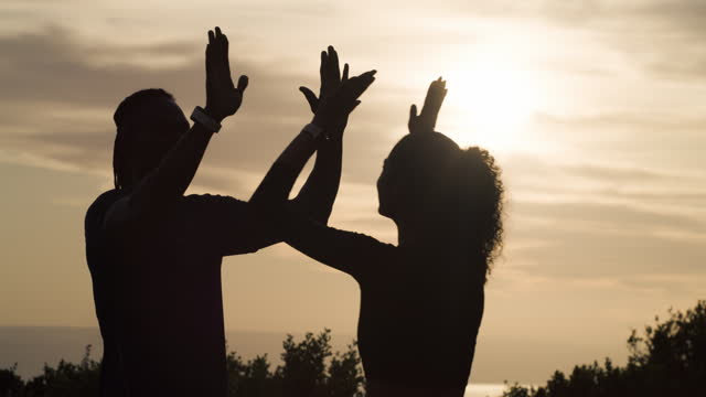 Sunset, fitness and couple high five in nature for training success, workout or milestone in nature. Sunrise, celebration and hands of sports people outdoor with energy, freedom and goal achievement