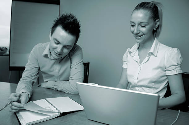 черный и белый-молодой женщины и мужчины, работающие в офисе - horizontal black and white toned image two people стоковые фото и изображения