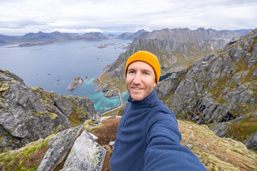 Man hikes in the mountains of Northern Norway, he looks at the camera, autumn