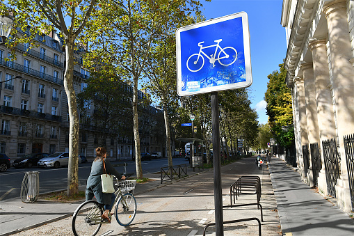 Paris, France-10 03 2023: A young woman cycling on a cycle path on a street in Paris, France.