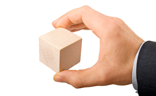 Hand holding a wooden cube.