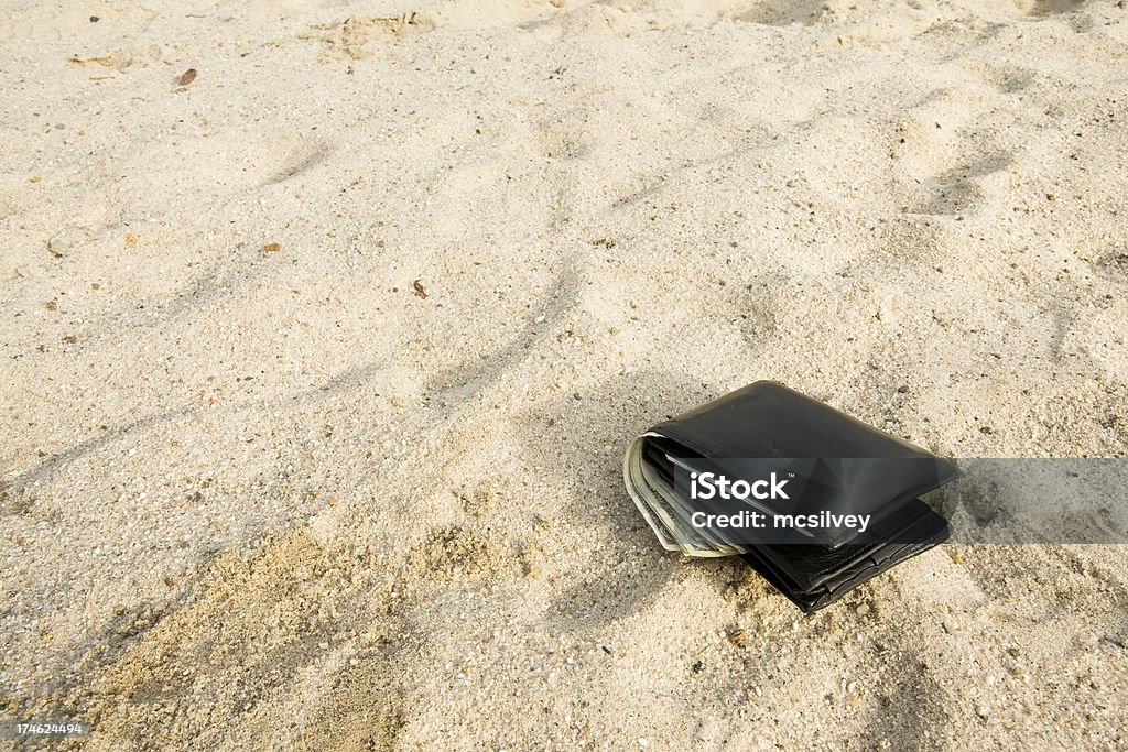 Wallet Lost in the Sand A black wallet with money laying forgotten a dropped in the sand.Part of the Lost Wallet SeriesMore Images from the Lost Wallet Series Wallet Stock Photo