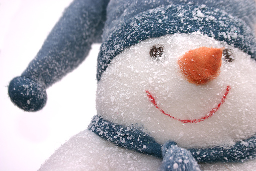 a shot of a toy snowman covered in snow and with a carrot for a nose!