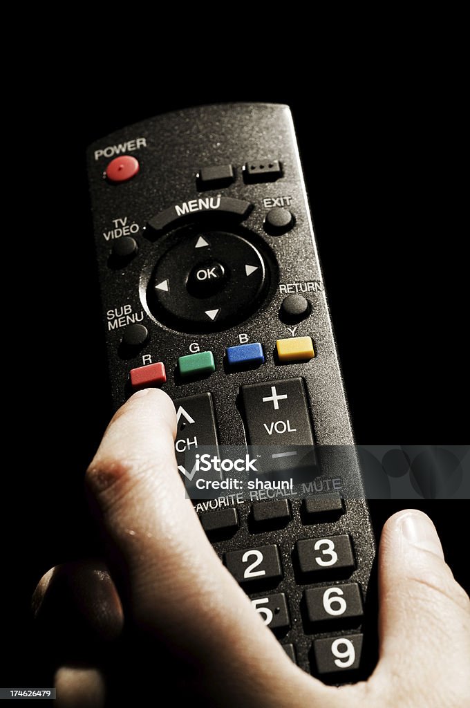 Television Remote Man holding a tv remote, channel surfing. Changing Channels Stock Photo