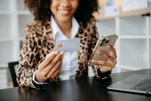 African Business woman hands using smartphone and holding credit card sitting. Online Shopping payments concept.