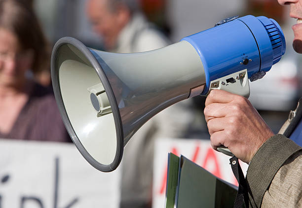 Person talking in a blow horn at a demonstration Close up of a megaphone during a demonstration. RAW-file developed with Adobe Lightroom. labor union stock pictures, royalty-free photos & images