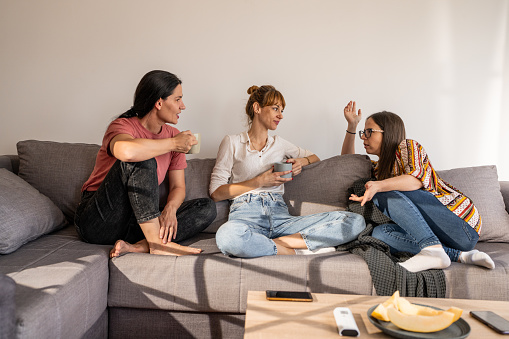 Female friends talking while sitting in living room at home.