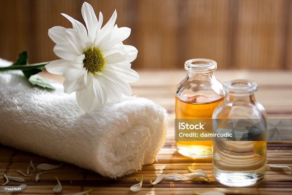 Aroma therapy oils placed next to a white towel and flower This is a photo that shows the things that are  Massaging Stock Photo