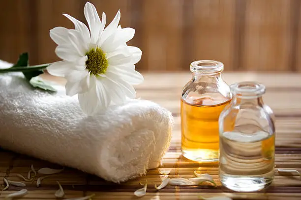 Photo of Aroma therapy oils placed next to a white towel and flower