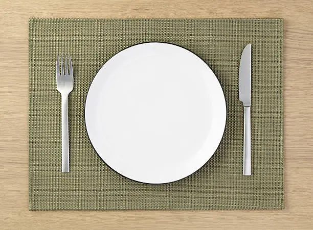 knife fork and plate on placemat and wooden table